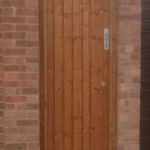 A wall with a gate in the middle. The gate has feather edge boards with a pre-clad timber frame.