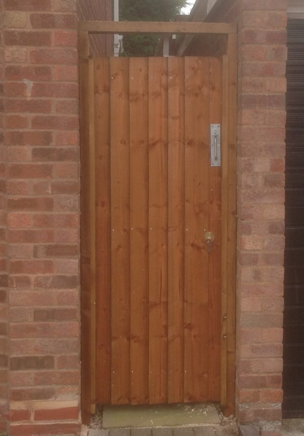 A wall with a gate in the middle. The gate has feather edge boards with a pre-clad timber frame.