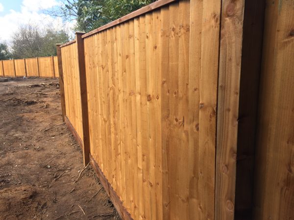 Pressure treated timber posts supporting wooden fence panels surrounding a empty area.