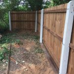 A wooden fence with concrete fence posts on display in a fencing supply yard.