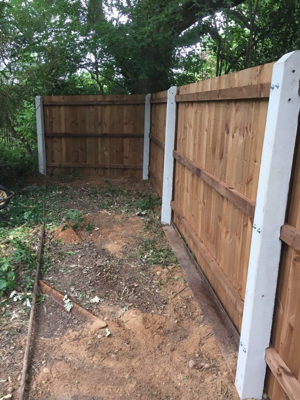 A wooden fence with concrete fence posts on display in a fencing supply yard.