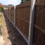 A wooden fence with multiple panels and concrete fence posts.