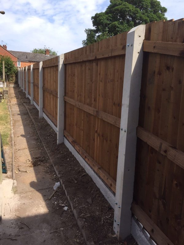 A wooden fence with multiple panels and concrete fence posts.