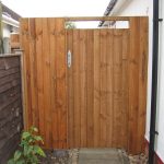 A wooden gates stands at the side of a house. The gate has feather edge boards with a pre-clad timber frame.