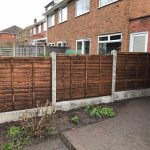 A house with a wooden fence alongside. The fence has z type timber panels which are double framed, overlapped with bevelled capping.