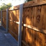 Concrete fence posts supporting wooden fence panels. The fence is on display in a supply yard in Birmingham.