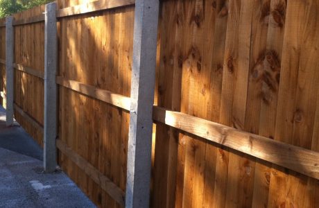 Concrete fence posts supporting wooden fence panels. The fence is on display in a supply yard in Birmingham.