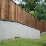 A large open area with a long fence. The fence has feather edge boards and is pressure treated.
