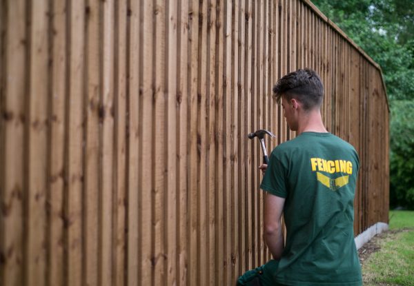 Hodges & Lawrence staff assembling a fence in a garden in Birmingham. The fence has feather edge boards.