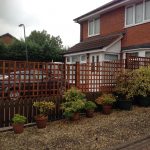Wooden fencing alongside a house. The fence has t type timber trellis fencing panels.