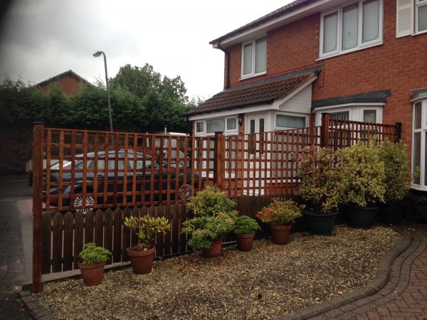Wooden fencing alongside a house. The fence has t type timber trellis fencing panels.