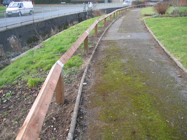 Bird mouth posts alongside a public walkway. The posts are pressure treated with a galvanised strap on each post.