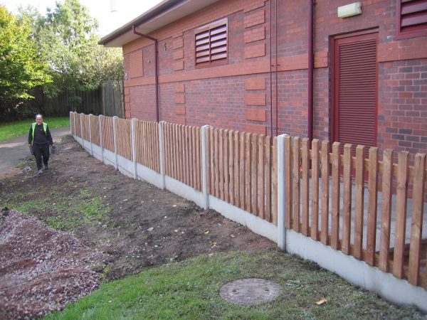 Hodges & Lawrence staff assembling a fence in a commercial area in Birmingham. The fence is constructed using timber pales.