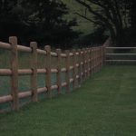 A large open field with round post fences. The fence is used for commercial purposes.