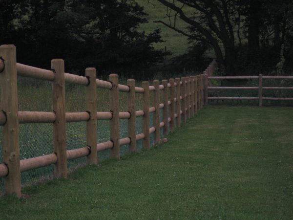 A large open field with round post fences. The fence is used for commercial purposes.