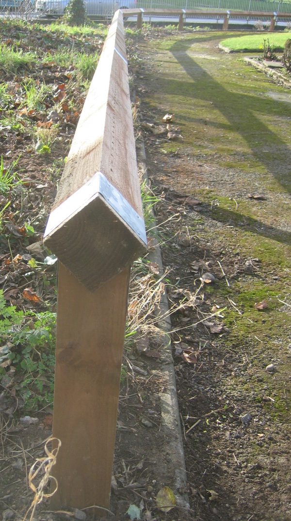 Bird mouth posts alongside a public walkway. The post is timber with steel strap.