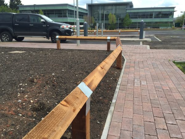 Bird mouth posts surround empty area next to a car park.