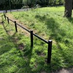 Steel trip rail along the perimeter of a open grassy area.