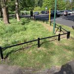 Steel trip rail surrounding a open grassy area.
